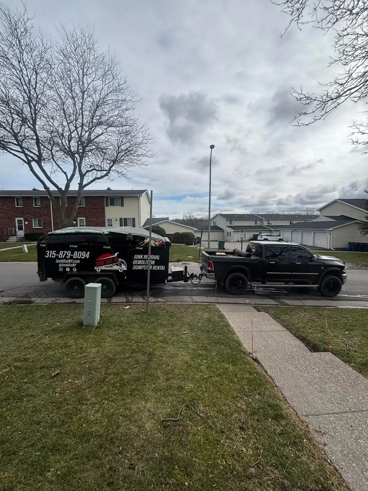 Junk Out NY truck and dump trailer parked at a Rochester area residential job site